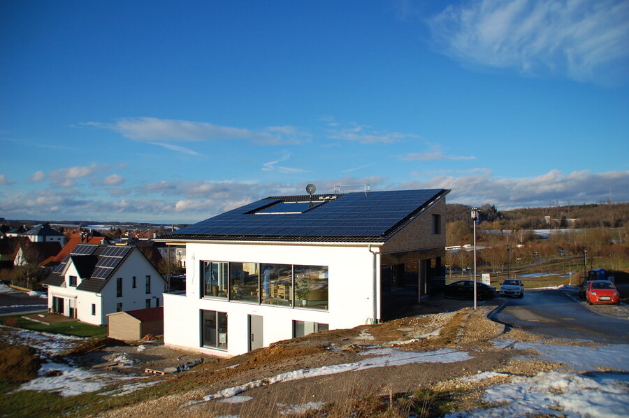 weißes Haus mit Aufdach-Solaranlage